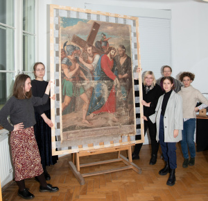 grupa studentów stojących przy konserwowanym obrazie