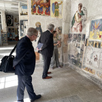 dwóch mężczyzn w garniturach podziwia malowidła ścienne w pracowni