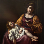 obraz przedstawiający Madonnę ubraną w karminowo urgową szatę. Na kolanach Matki Boskiej spoczywa śpiące dzieciątko Jezus ubrane w białą koszulę